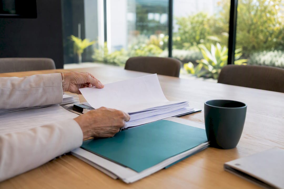 Hands reviewing audit records at real estate office desk