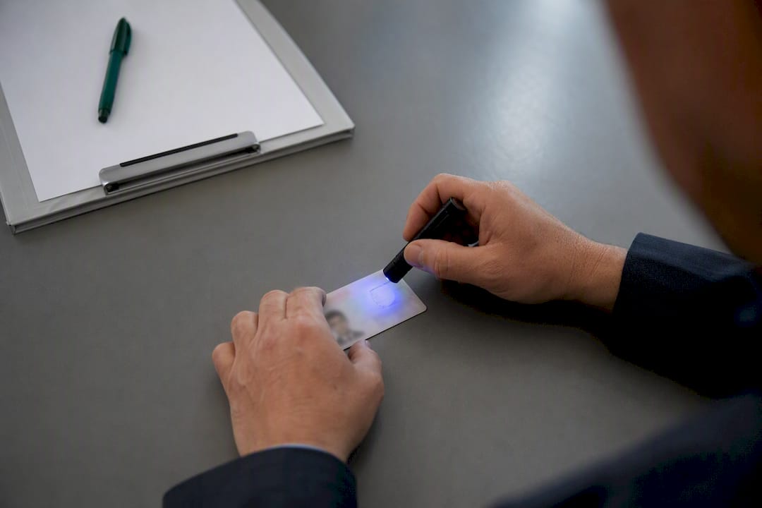 Hands using UV pen light to check ID
