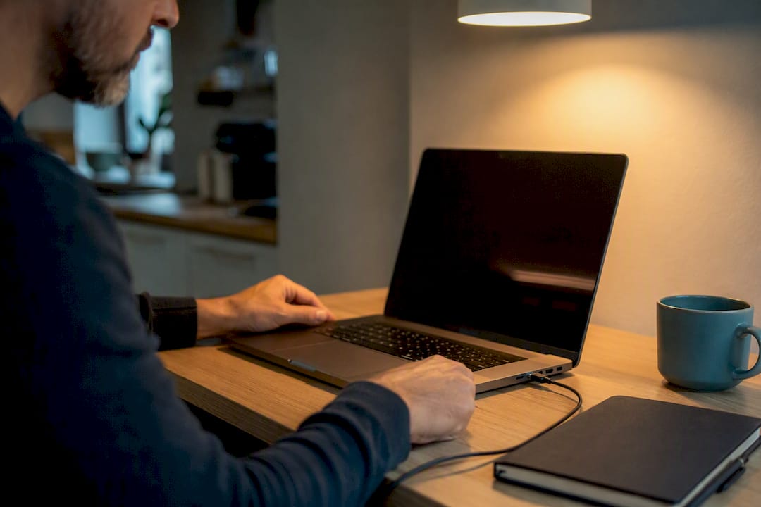 Person plugging in laptop charger on desk